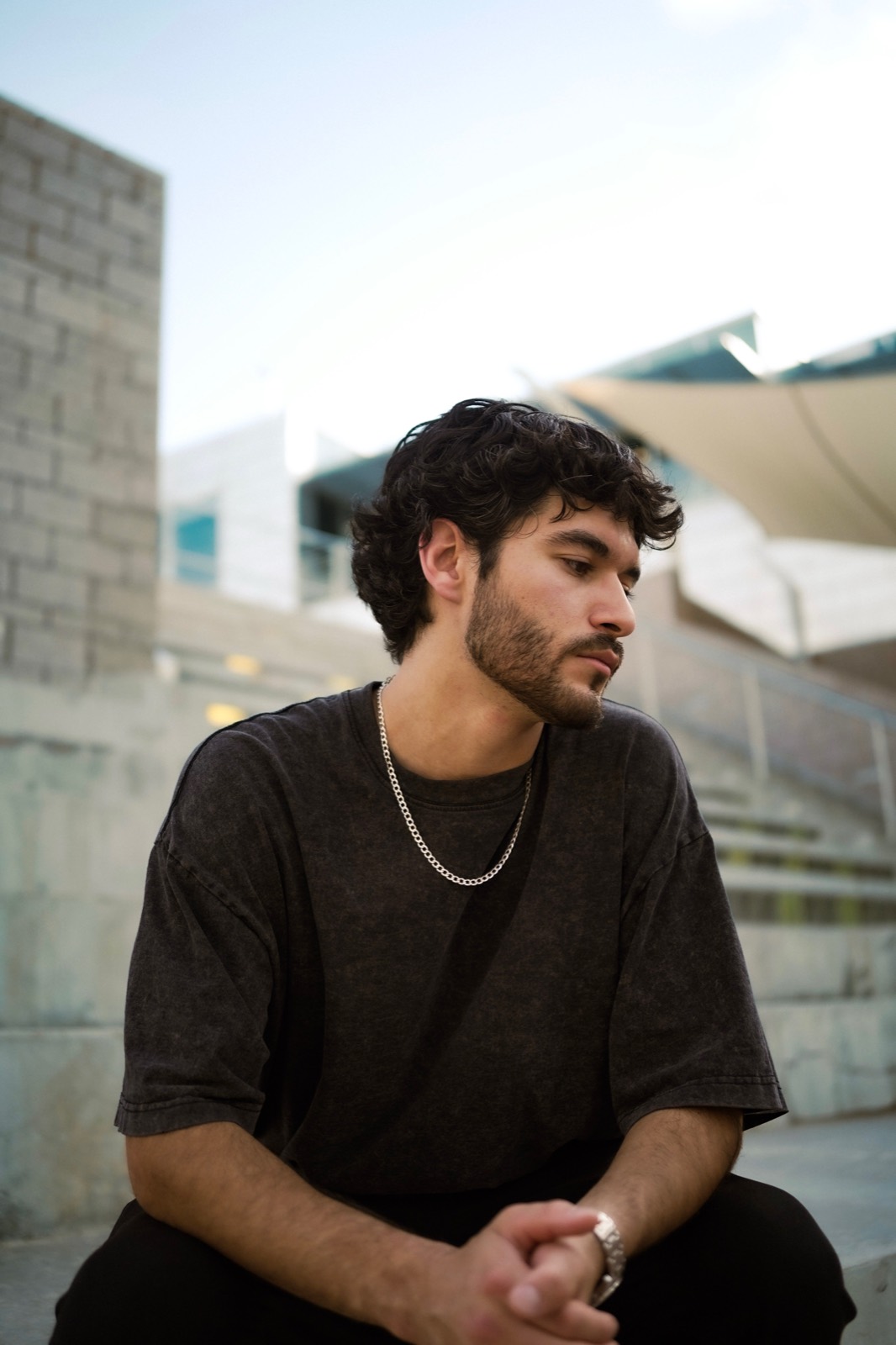 IVAN. seated in front of a concrete building in daylight